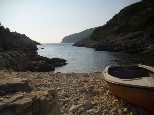 An artistic view of avlaki beach in paxos with a small boat parked on the land.